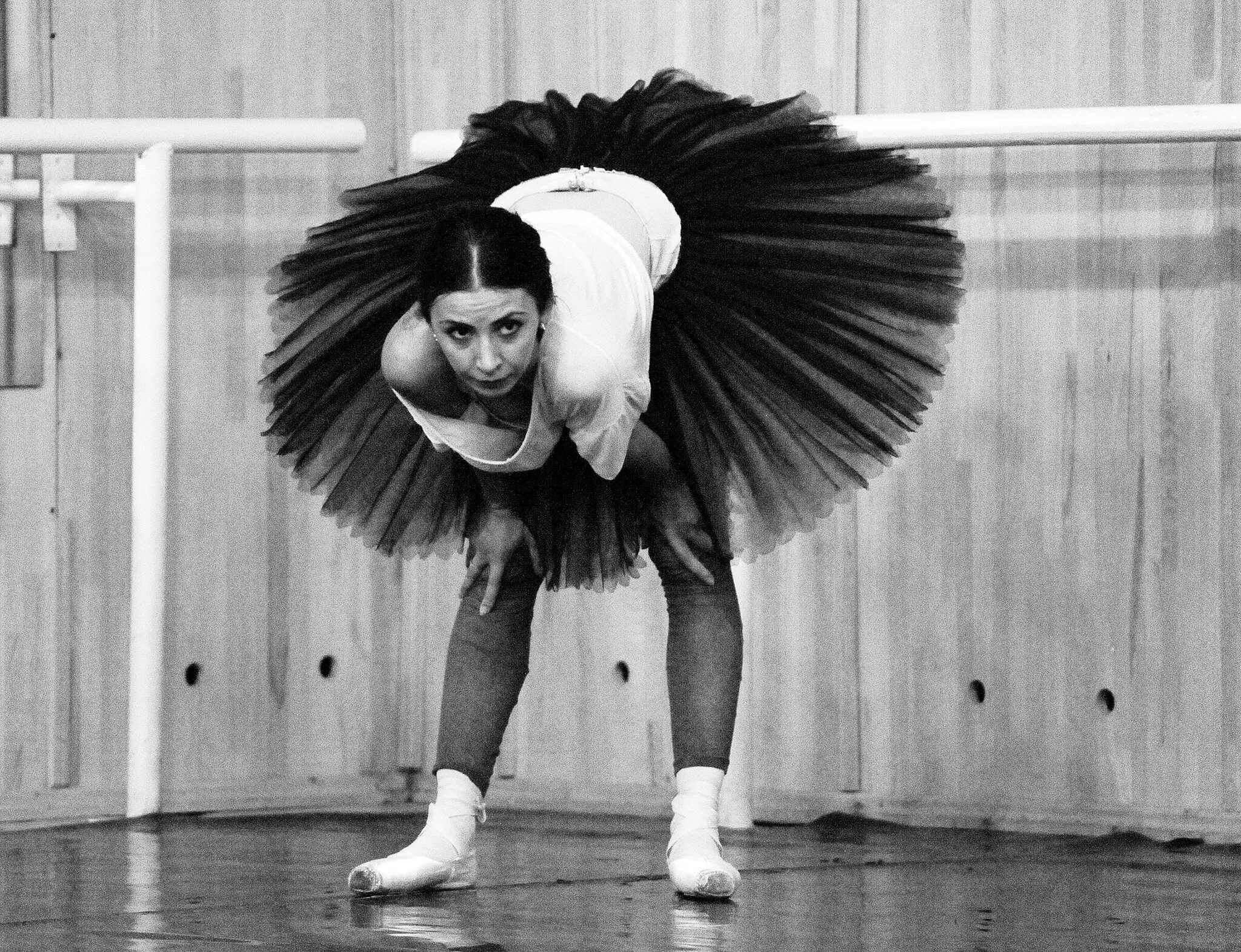 En studio, une danseuse en tutu saluant, photographie en noir et blanc.
