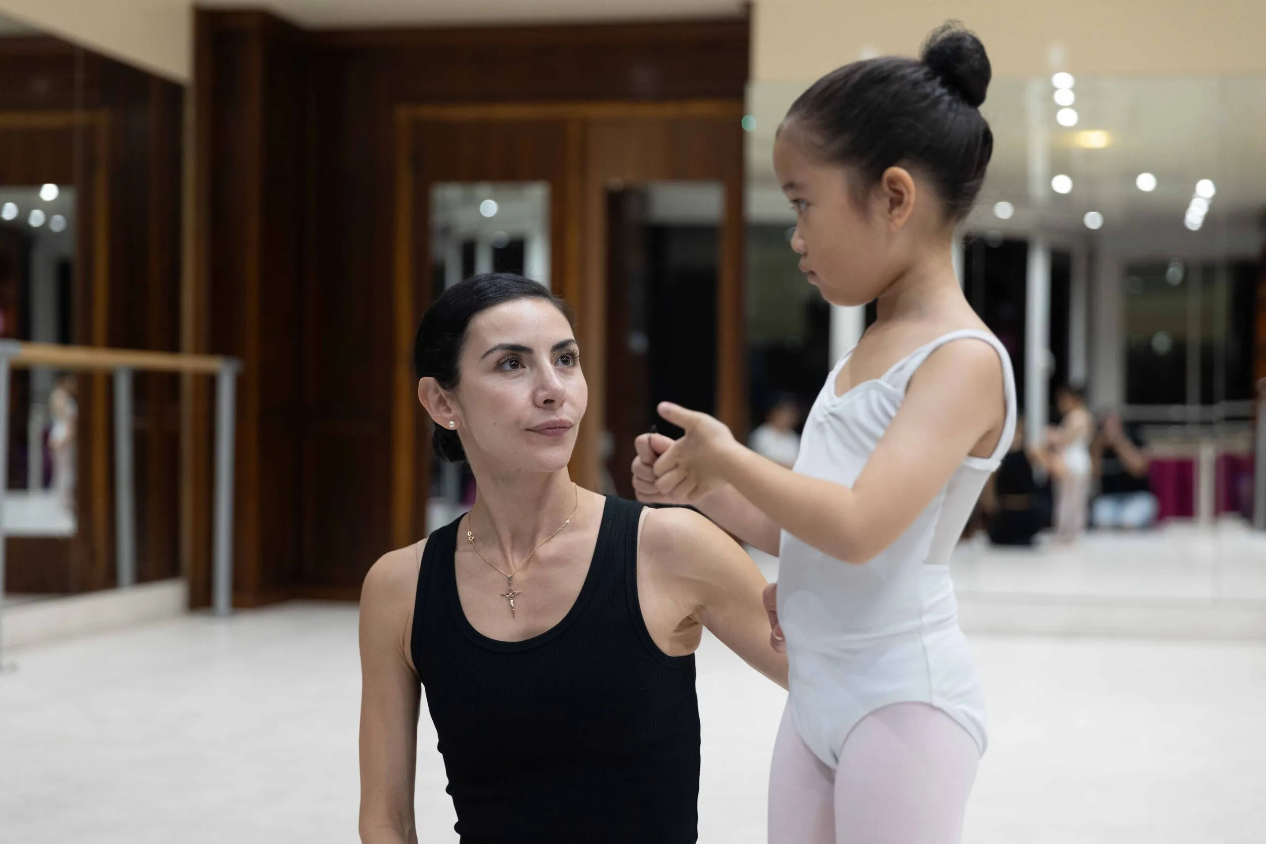 Une professeure corrigeant une élève à la barre.