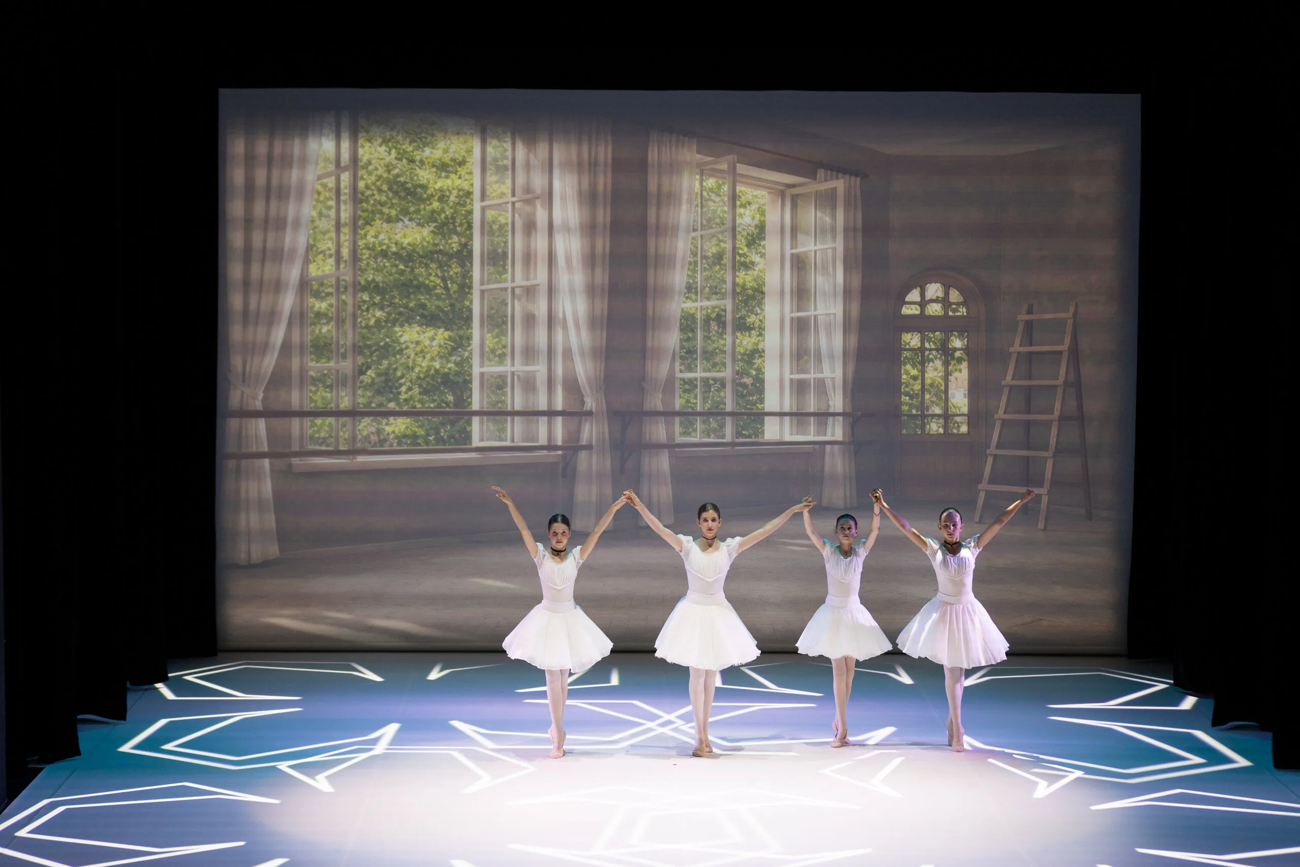Quatre élèves en blanc ouvrent le spectacle, la salle de classe en toile de fond.