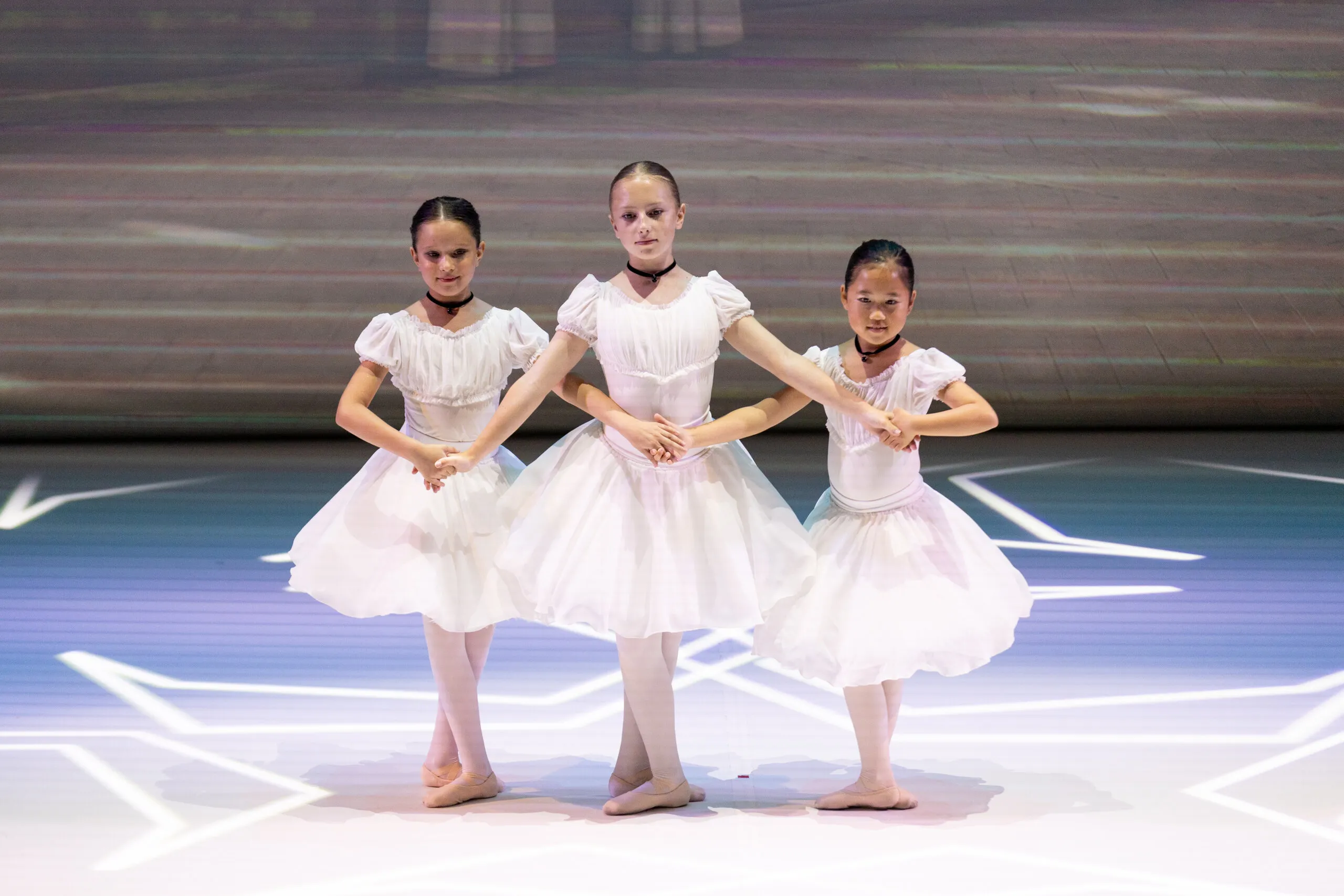 Trois élèves en robes blanches, mains jointes.