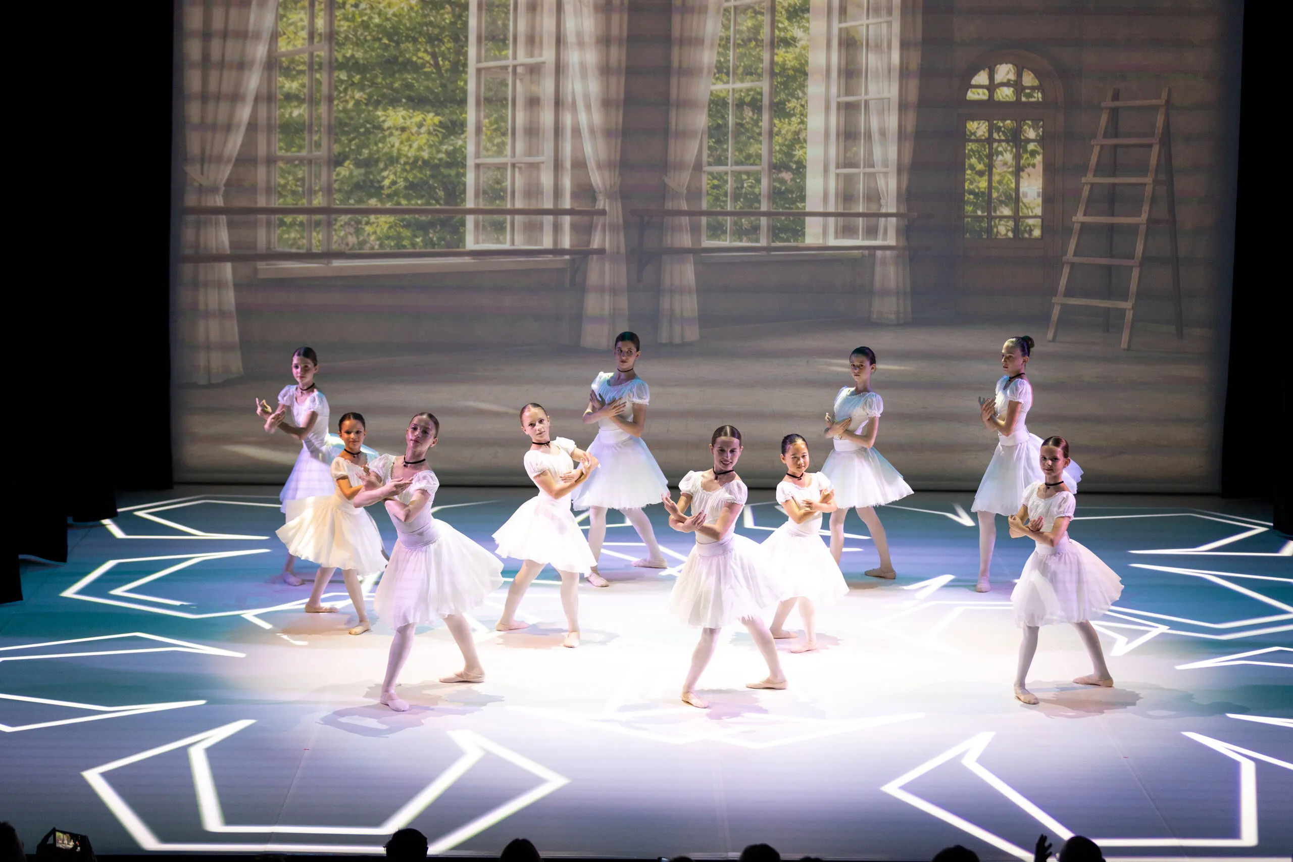Le groupe en blanc réparti sur le plateau, motif de flocon au sol.