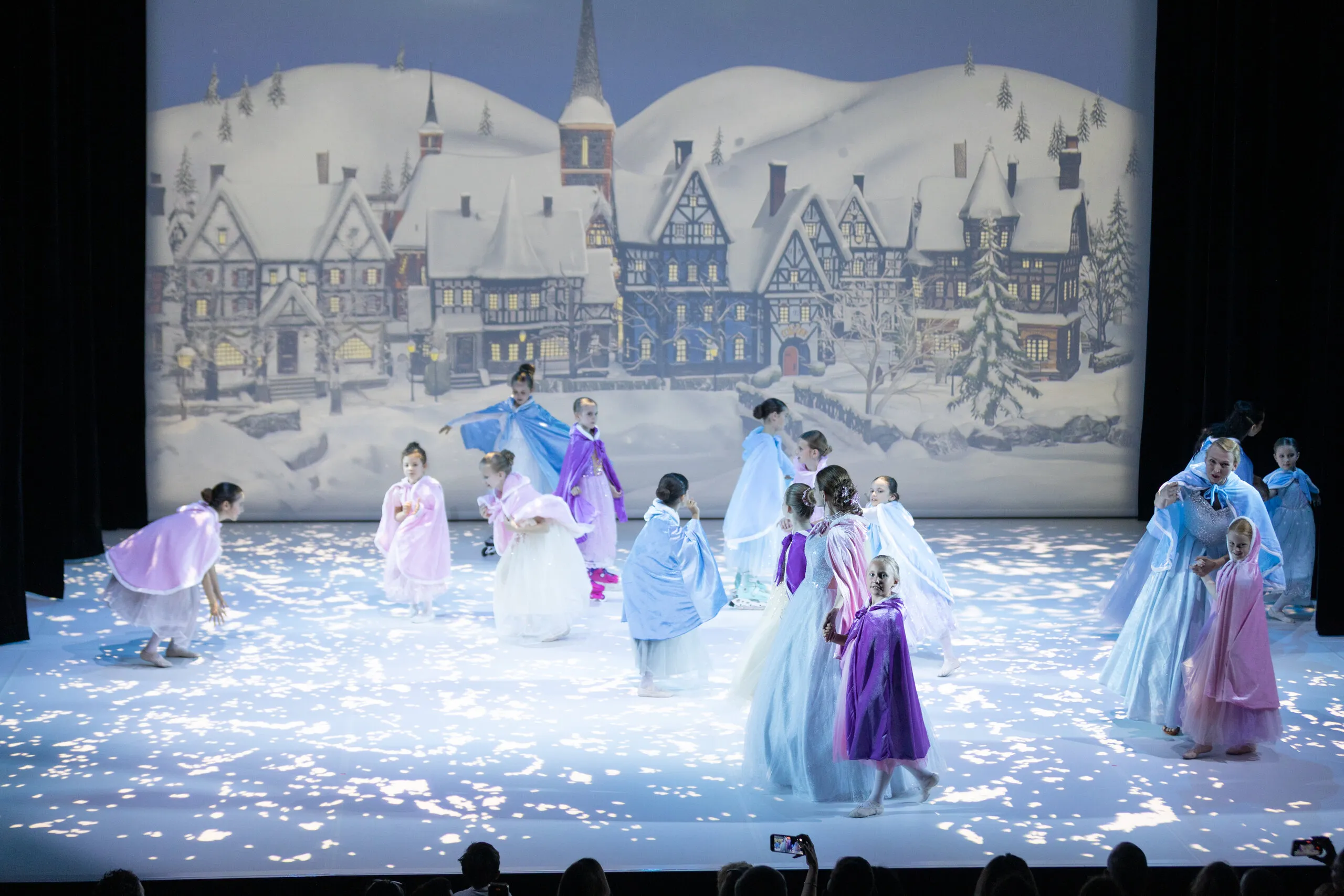 La scène du village sous la neige, tout le groupe en capes.