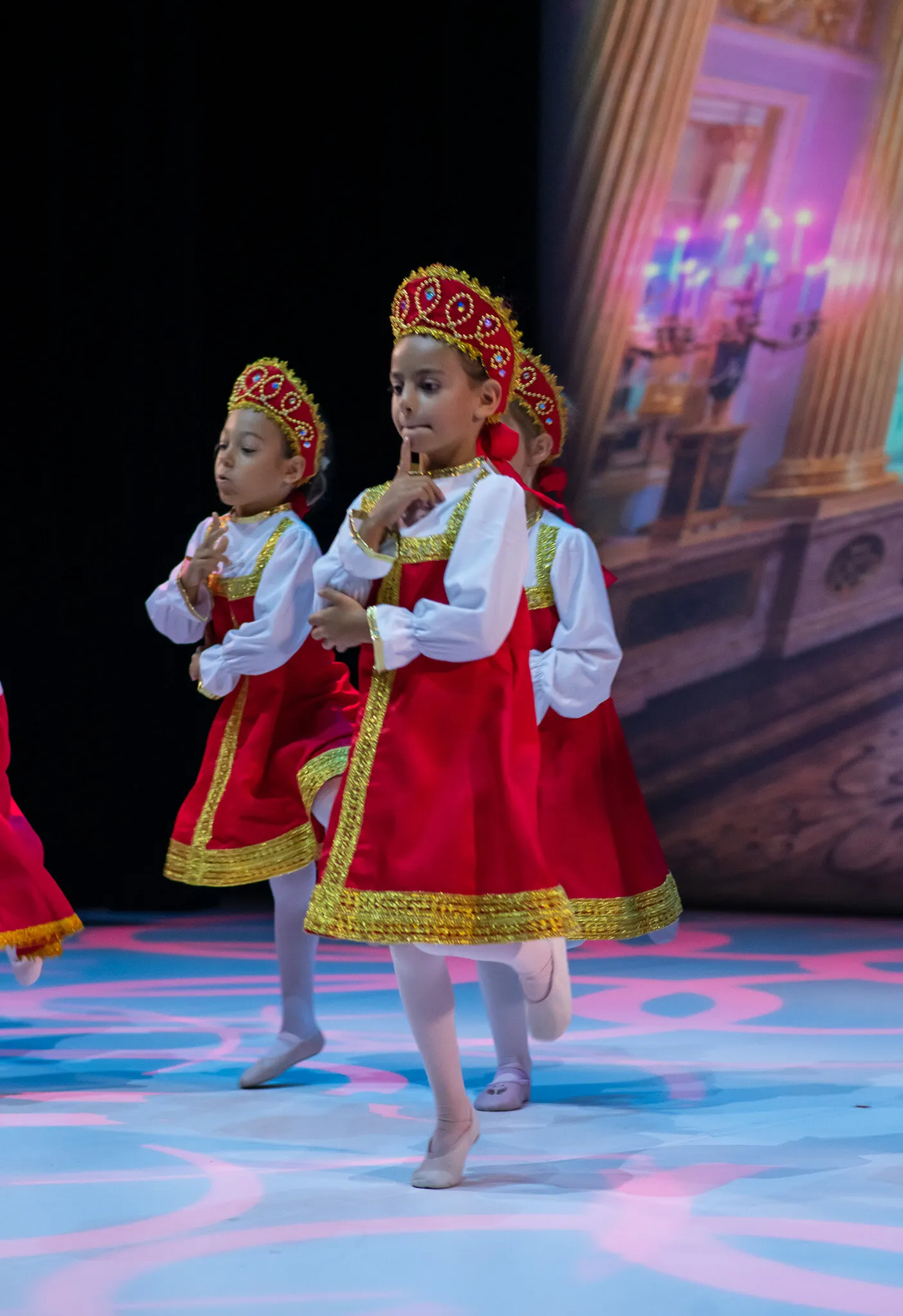 Deux jeunes élèves en costume rouge et or traversent le plateau pendant la générale.