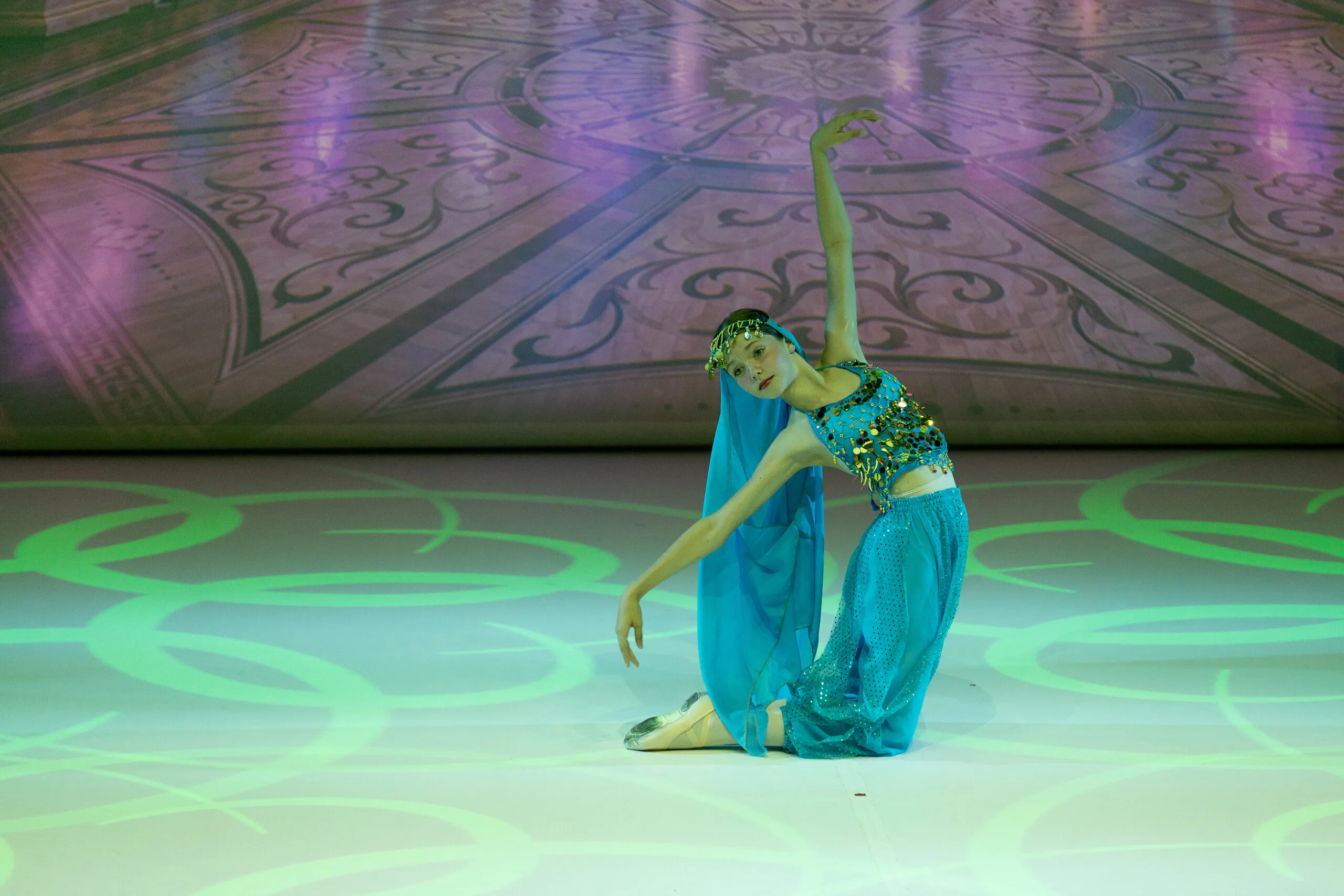 La danse arabe, à genoux dans la lumière verte, le bras levé.