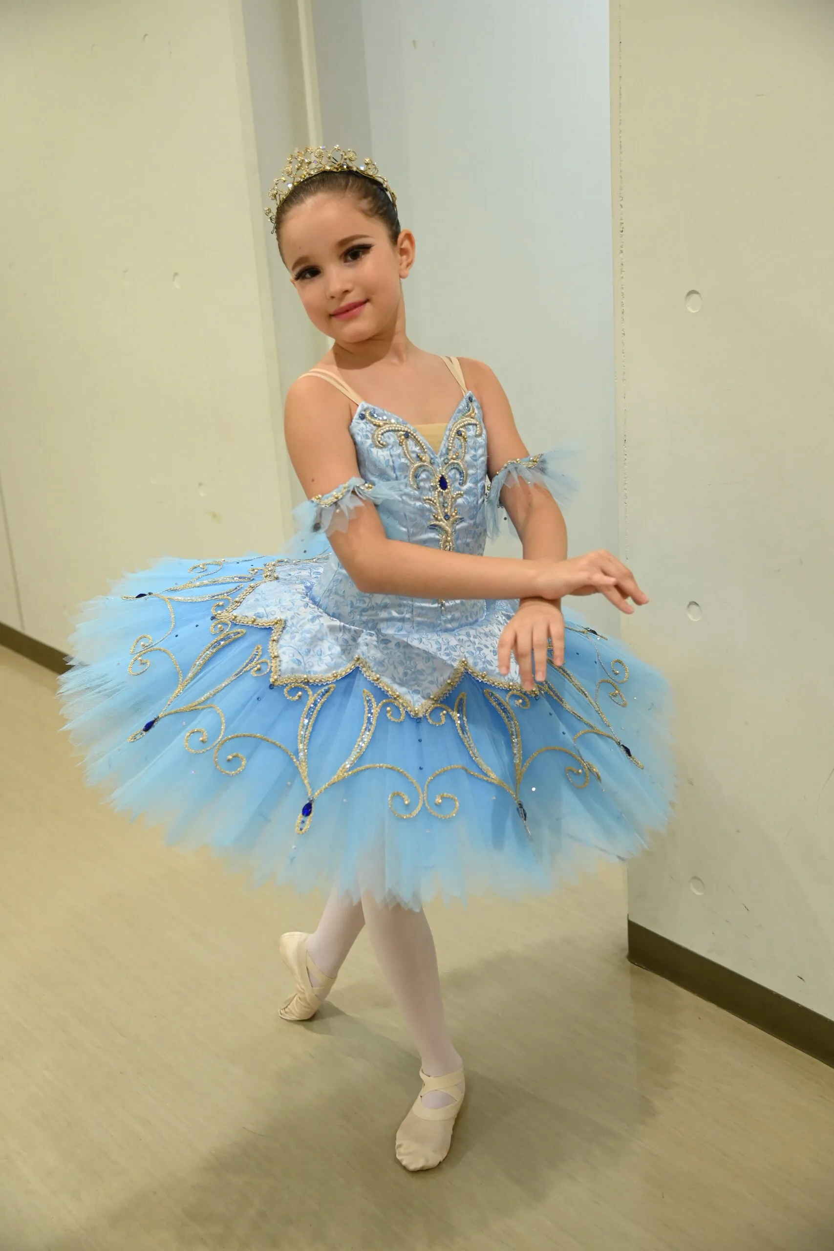 Une élève en tutu bleu, figure entière, dans le couloir des loges.