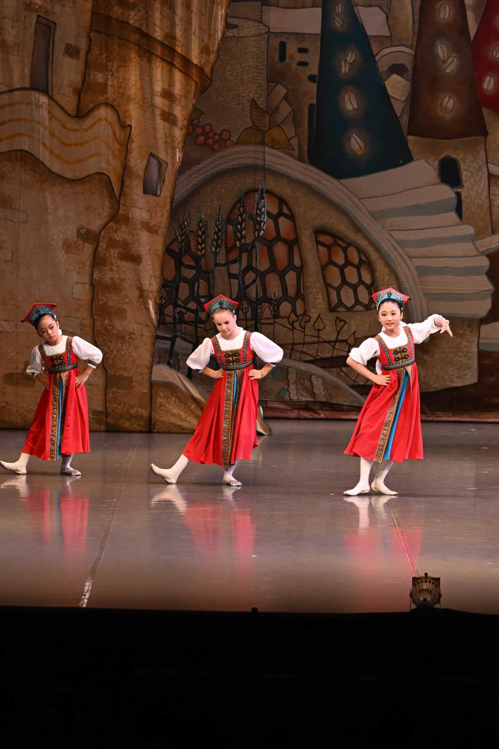 Trois danseuses en capes rouges, en diagonale.