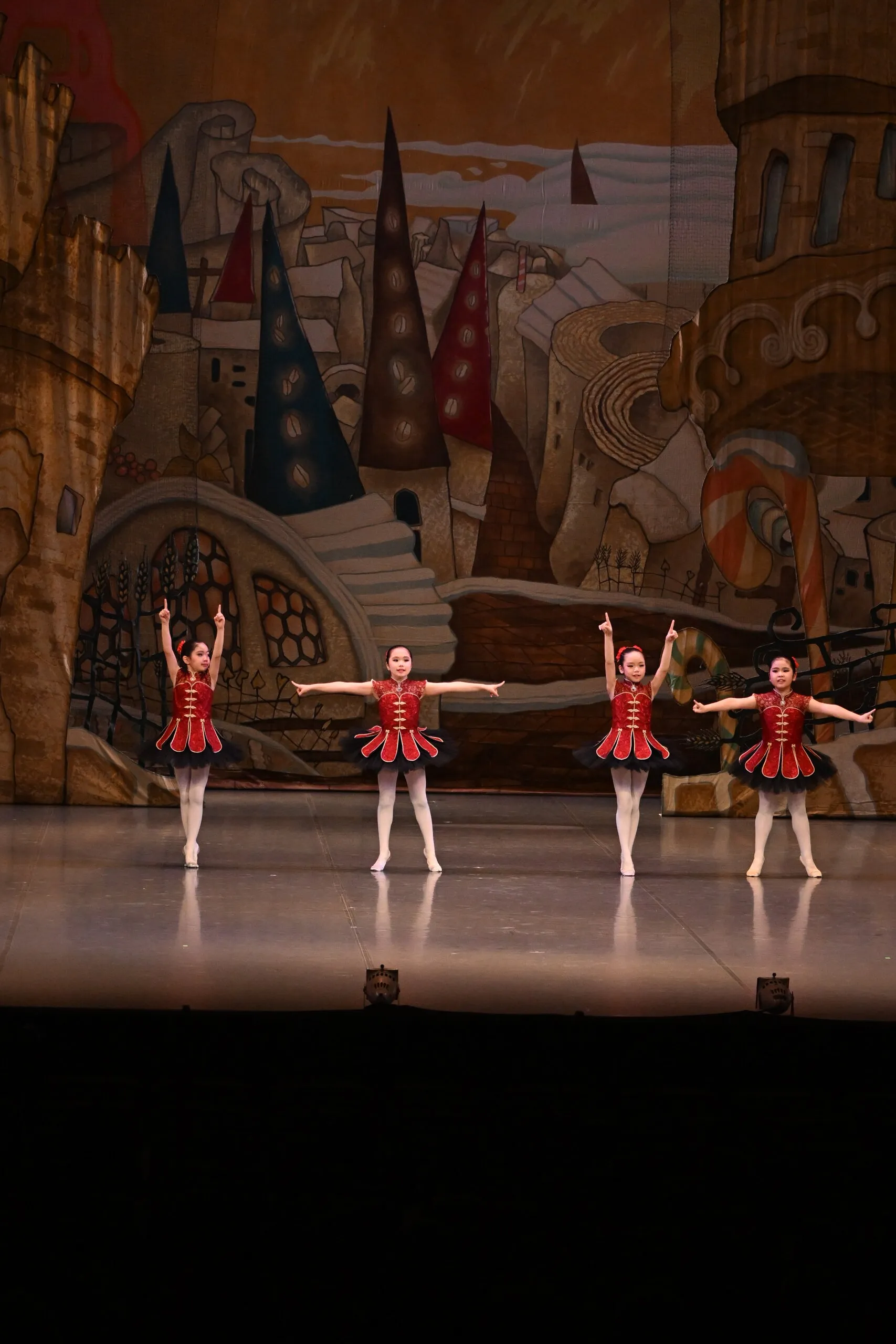Ligne de danseuses en costumes rouges devant le décor.