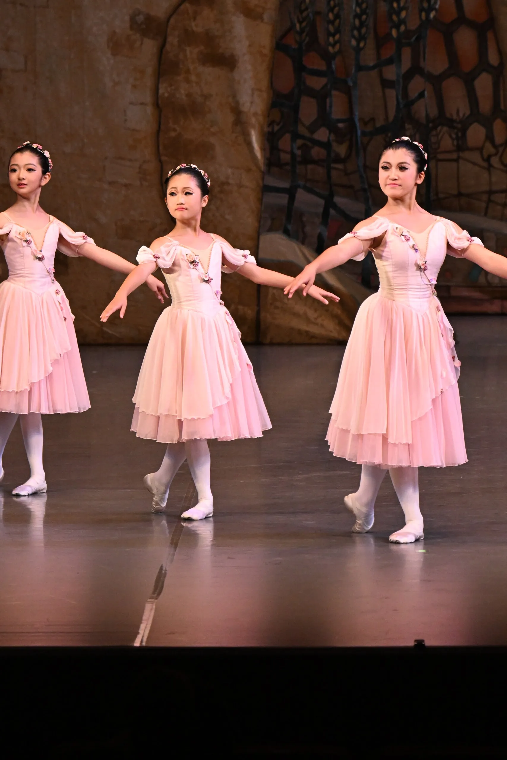 Trois élèves en robes roses s'avancent ensemble.