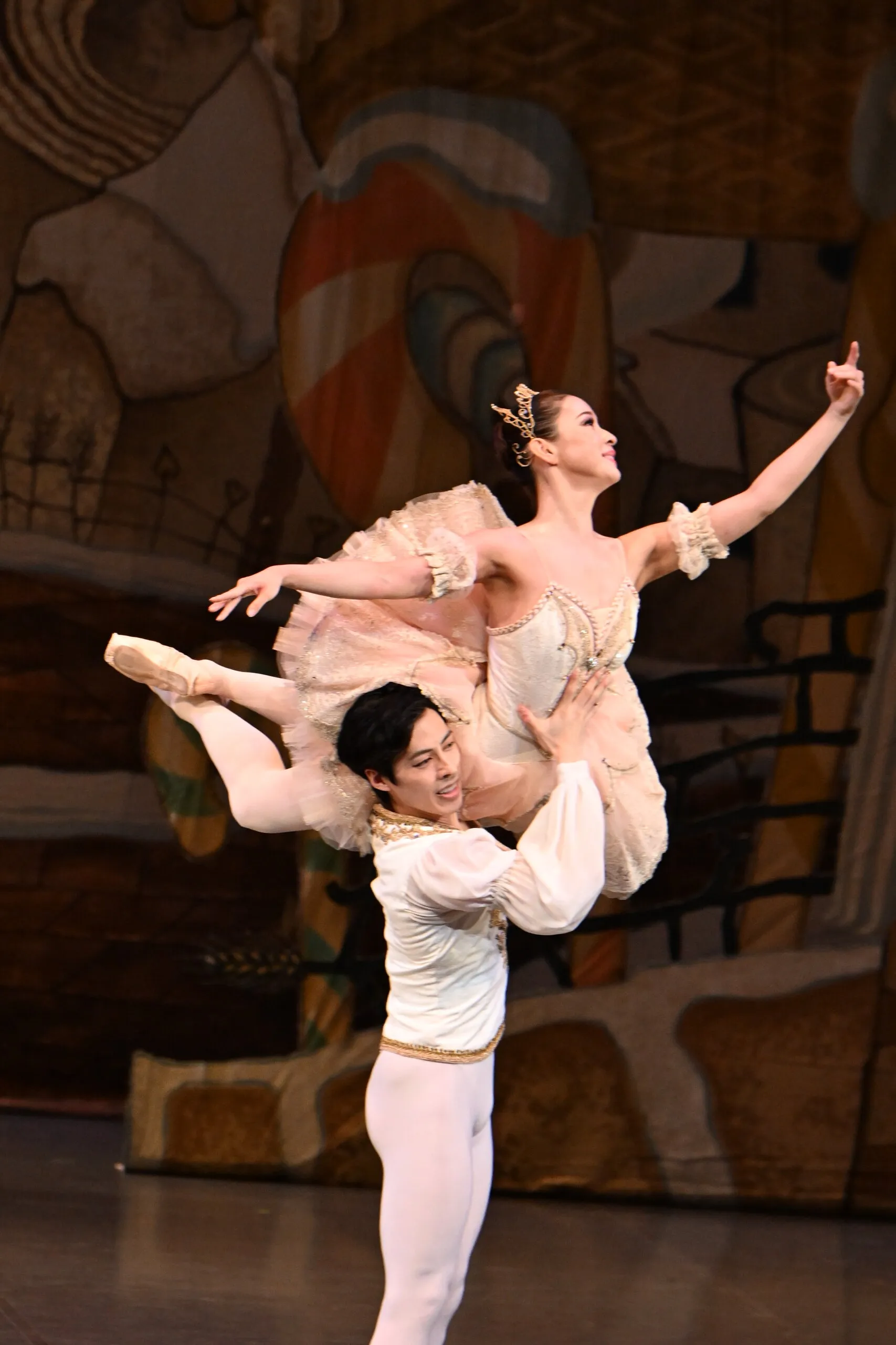 Pas de deux, la danseuse portée par son partenaire, lumière chaude.