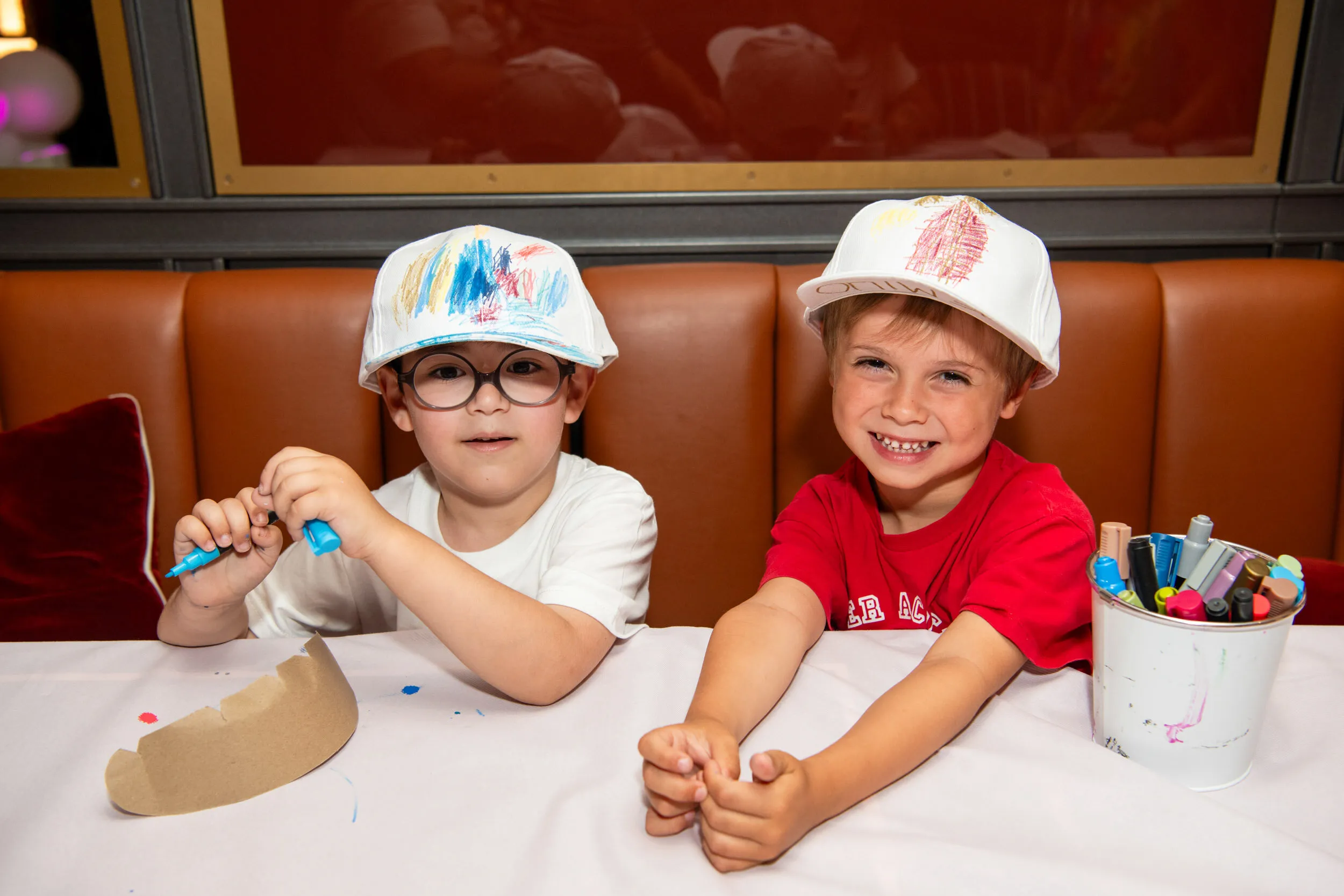 Deux garçons montrent fièrement les casquettes qu'ils ont décorées.