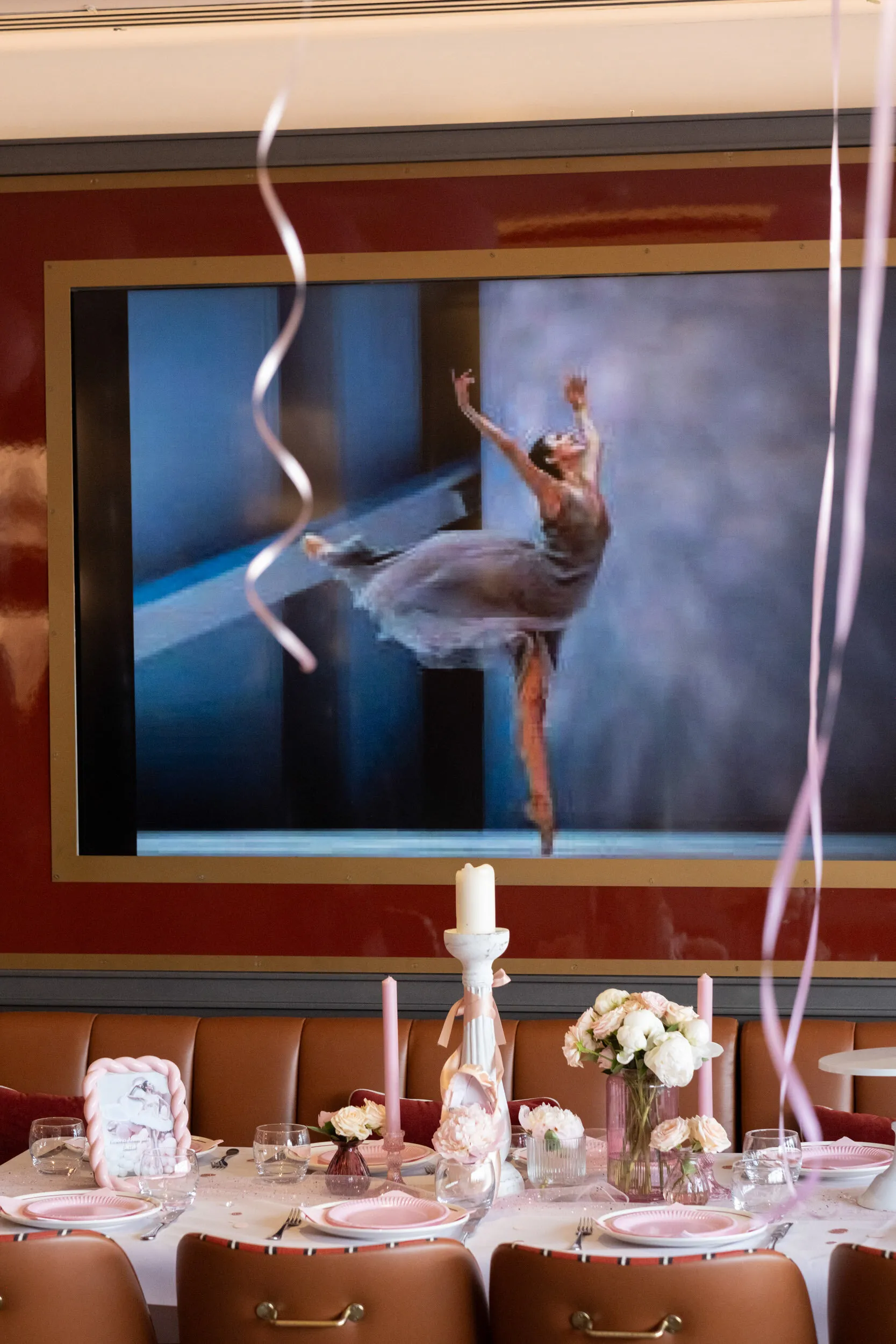 Une ballerine projetée à l'écran au-dessus de la table dressée, bougies et fleurs blanches.